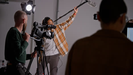 Male-Sound-Recordist-And-Camera-Operator-Working-On-Film-Set-Shooting-Movie-Or-Video-In-Studio-Shot-In-Real-Time